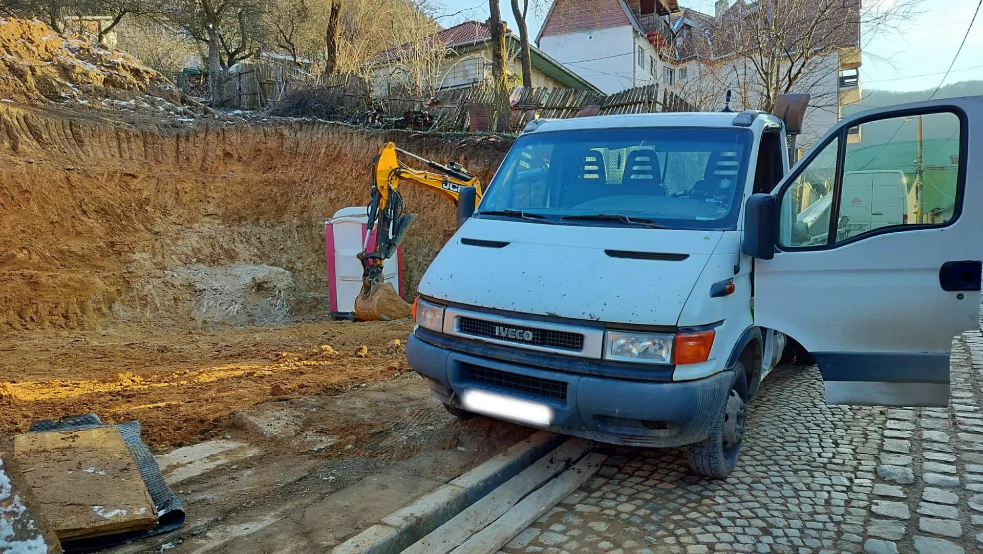 Autoutilitară parcată lângă o excavare mare și un mini excavator