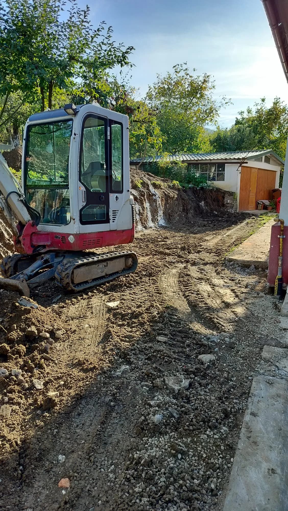 Mini excavator pe aleea de acces după terasarea terenului