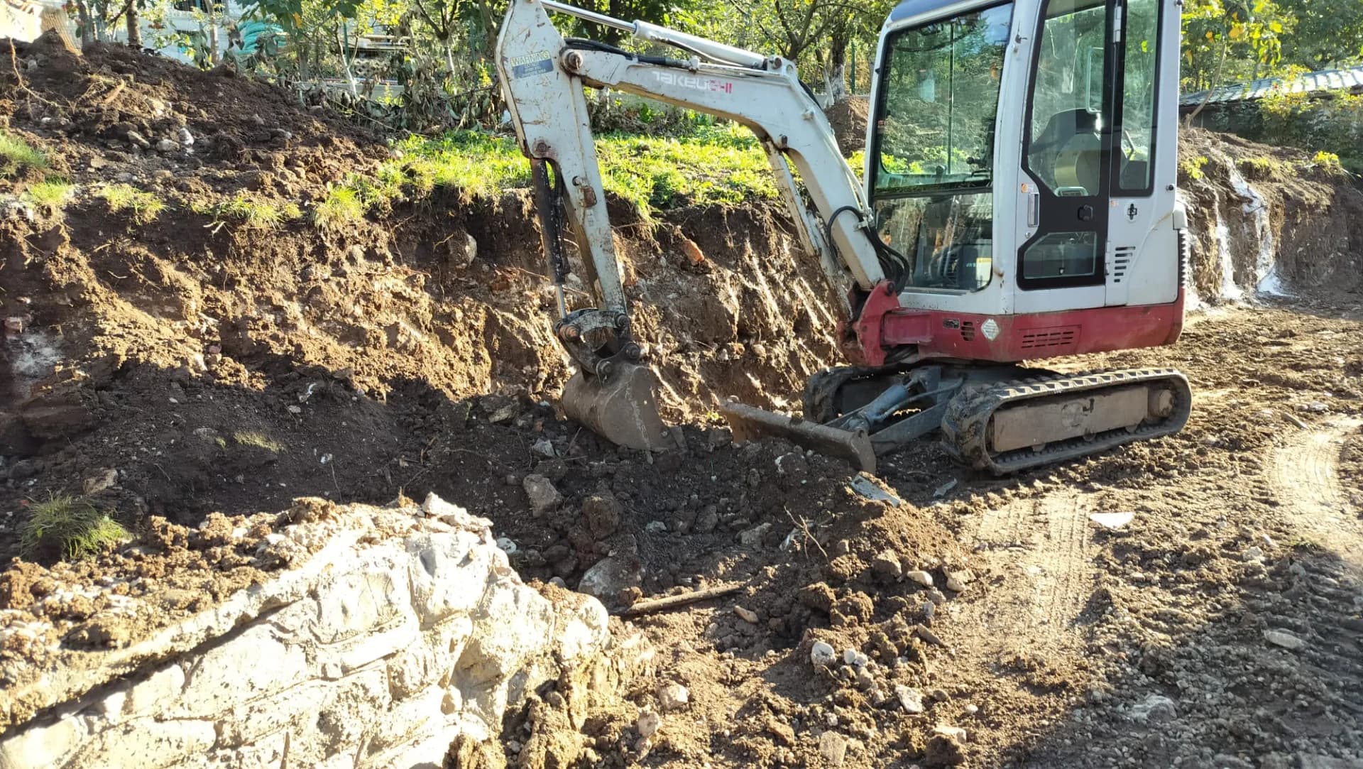 Mini excavator pe teren nivelat pentru amenajare în curte