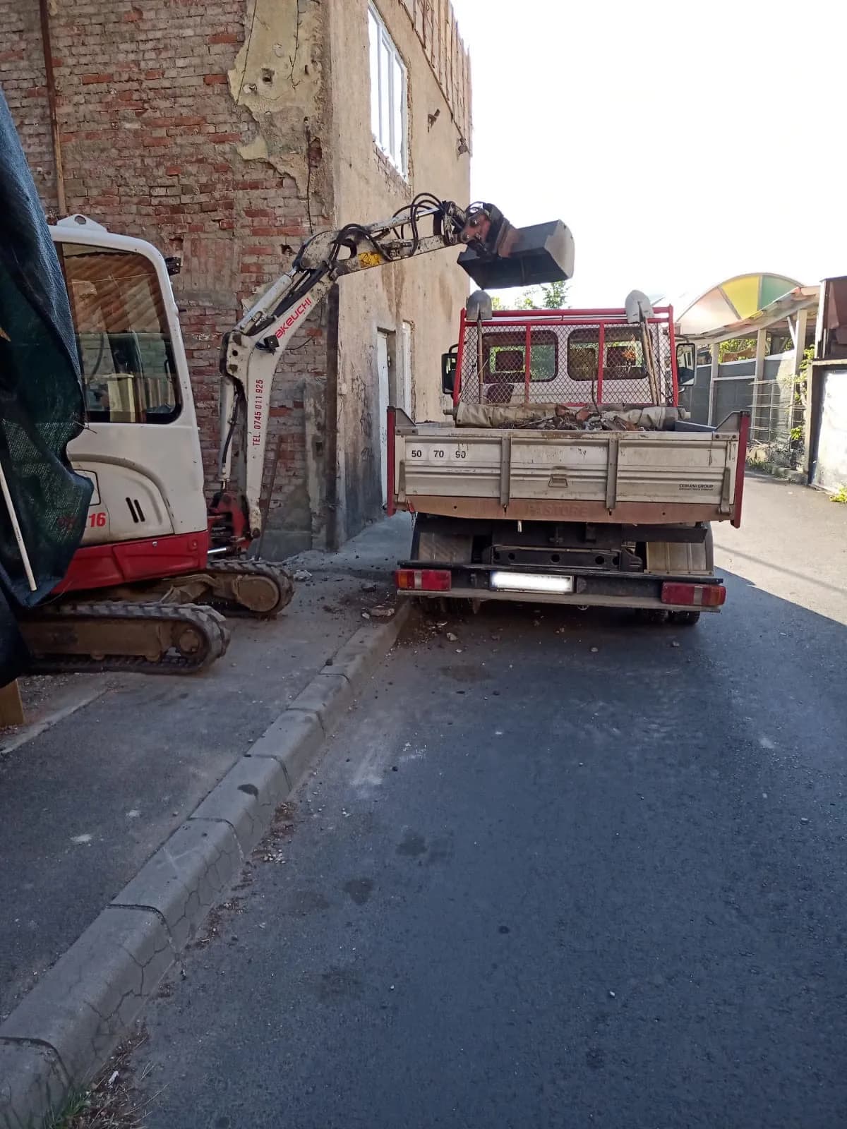 Încărcare moloz cu mini excavator pe șantier