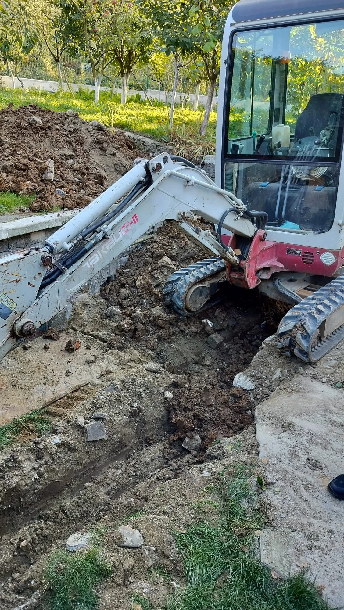 Șanț săpat cu mini excavator lângă gard și intrarea în curte