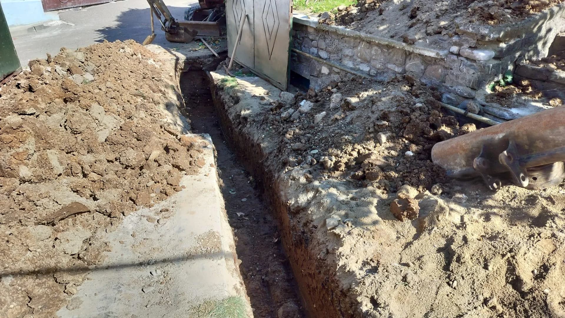 Șanț săpat lângă poartă și zidul de împrejmuire pentru lucrări de utilități