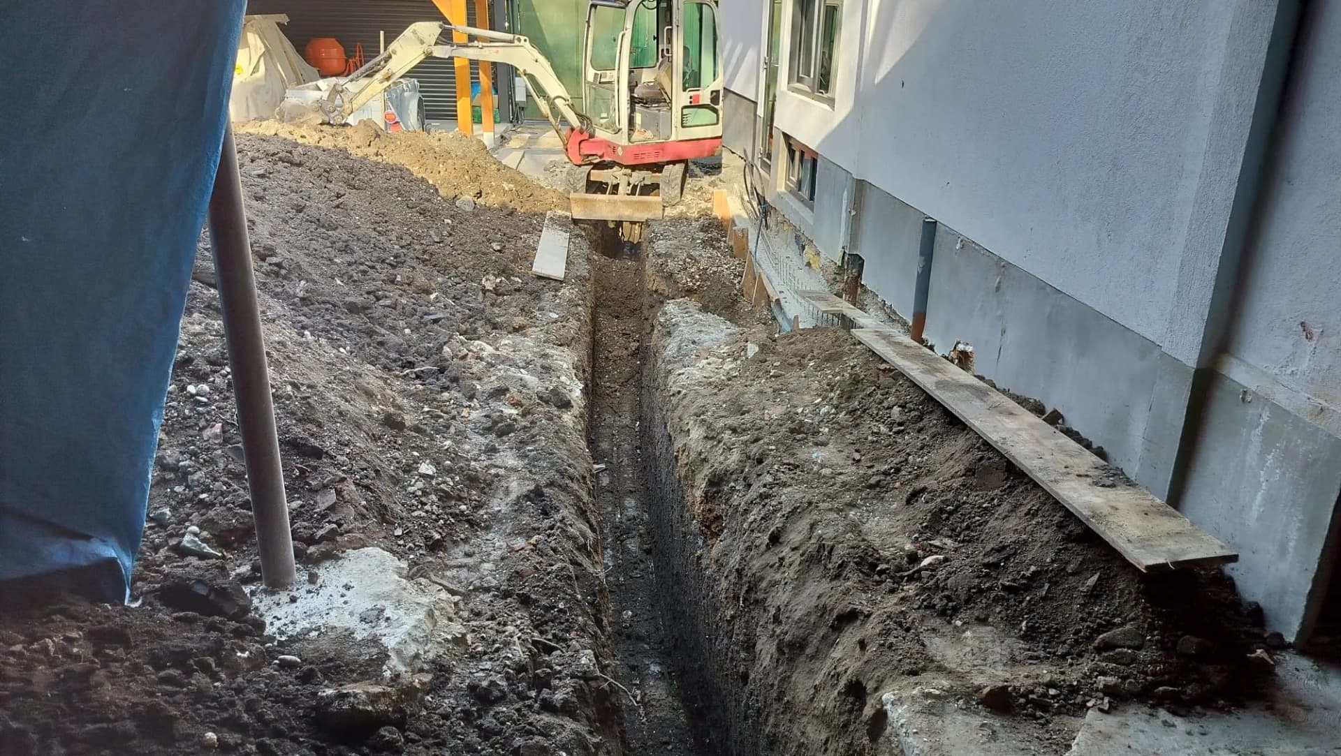 Săpătură lungă lângă casă pentru fundație sau utilități